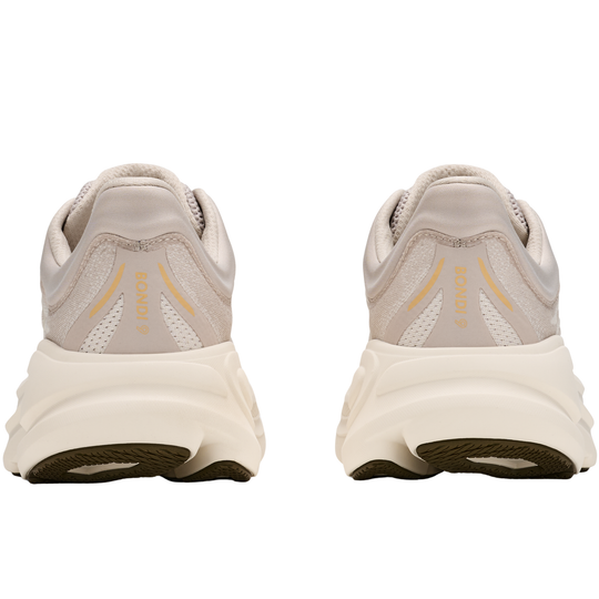 Pair of beige running shoes with a white sole on a white background