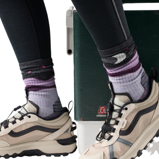 Someone wearing a pair of Purple socks with a pair of hiking shoes on.