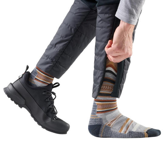 Person wearing multi colored socks and a hiking shoe on a white background