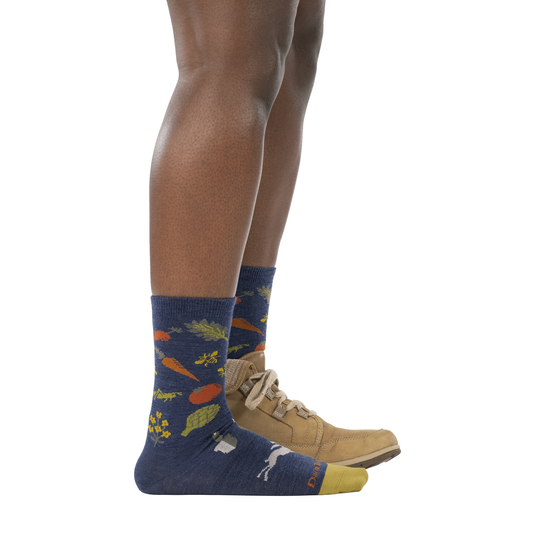 Person wearing blue socks with carrot design and tan shoes on a white background