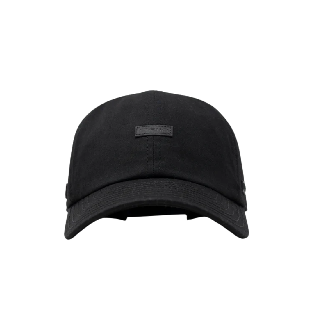 A black baseball cap with a curved brim and a small rectangular black logo patch on the front, shown against a plain white background.