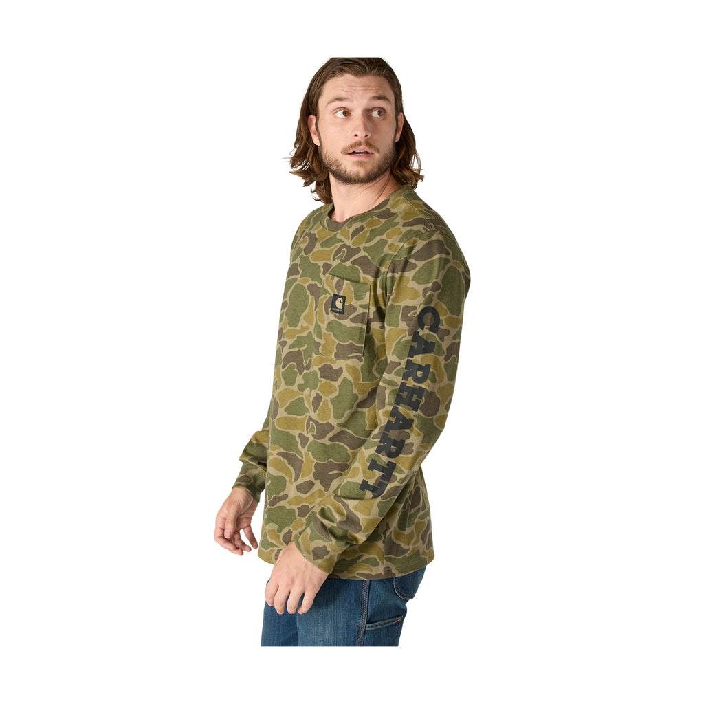 Man wearing a green camouflage long-sleeve shirt with 'Carhartt' branding on a white background