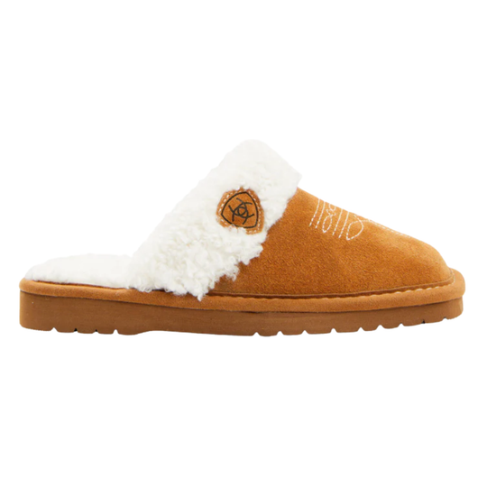 A single slip-on mule slipper in tan suede with a white sherpa lining and a small circular brown logo patch on the side, shown against a plain white background.