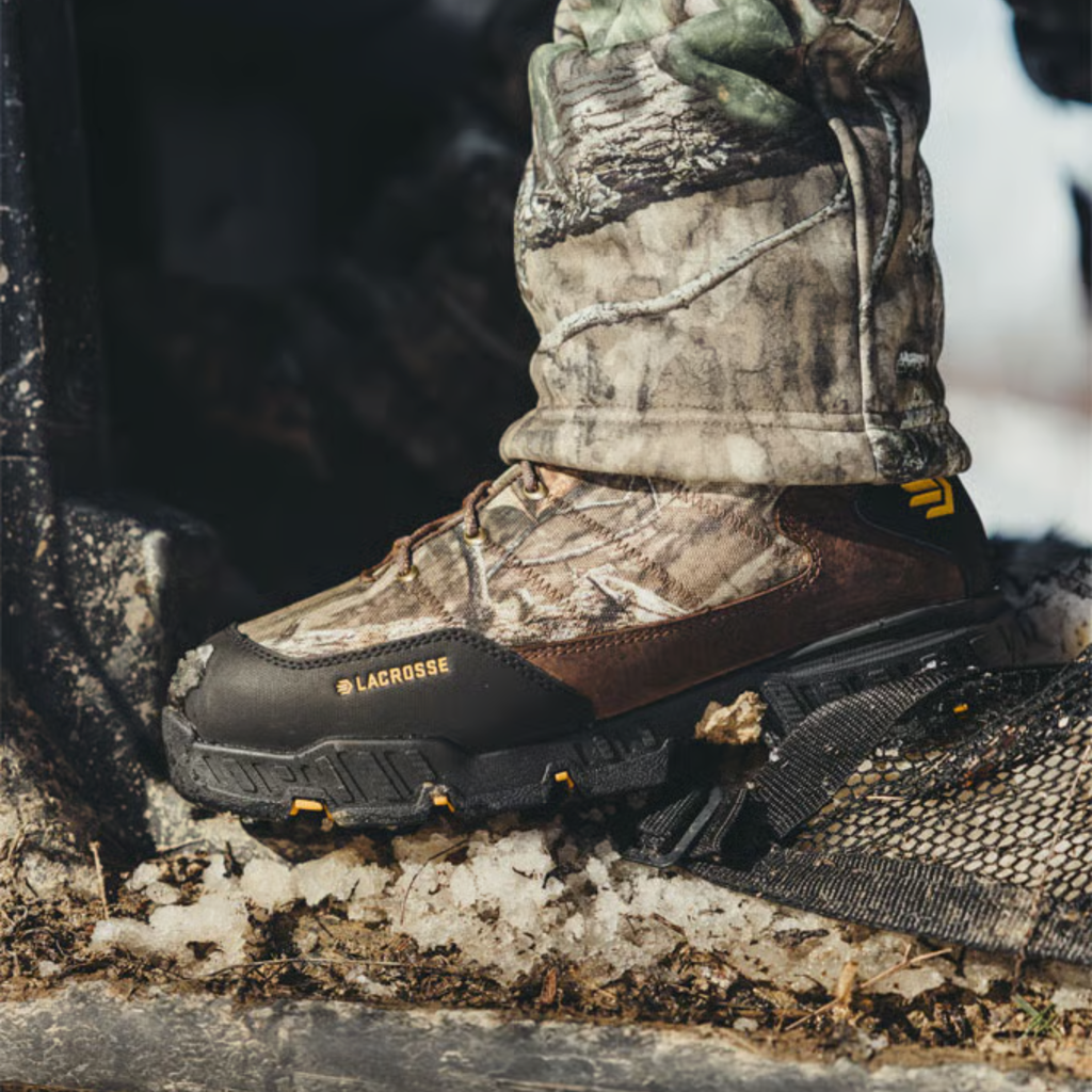 Camouflage hunting boot with visible brand name on a snowy ground