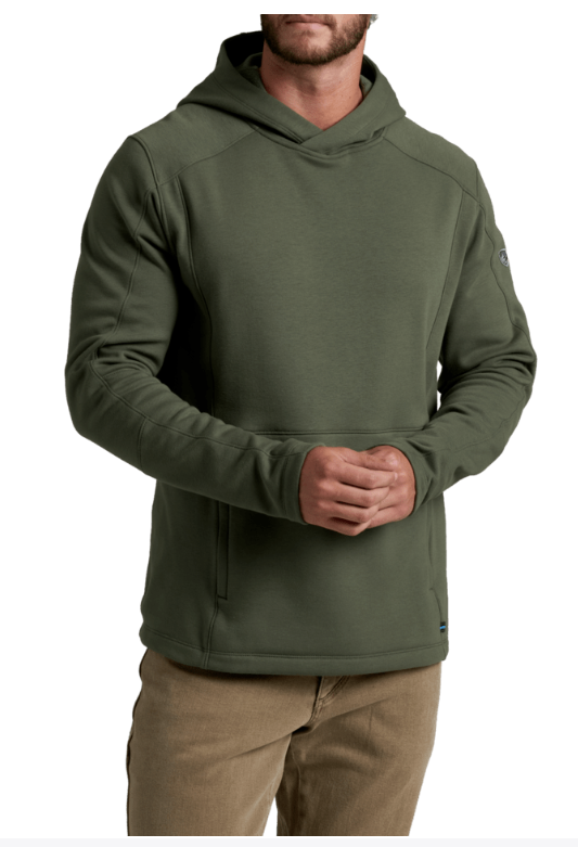 A man wearing an olive green hooded sweatshirt with a kangaroo pocket, paired with tan pants, shown against a plain white background.