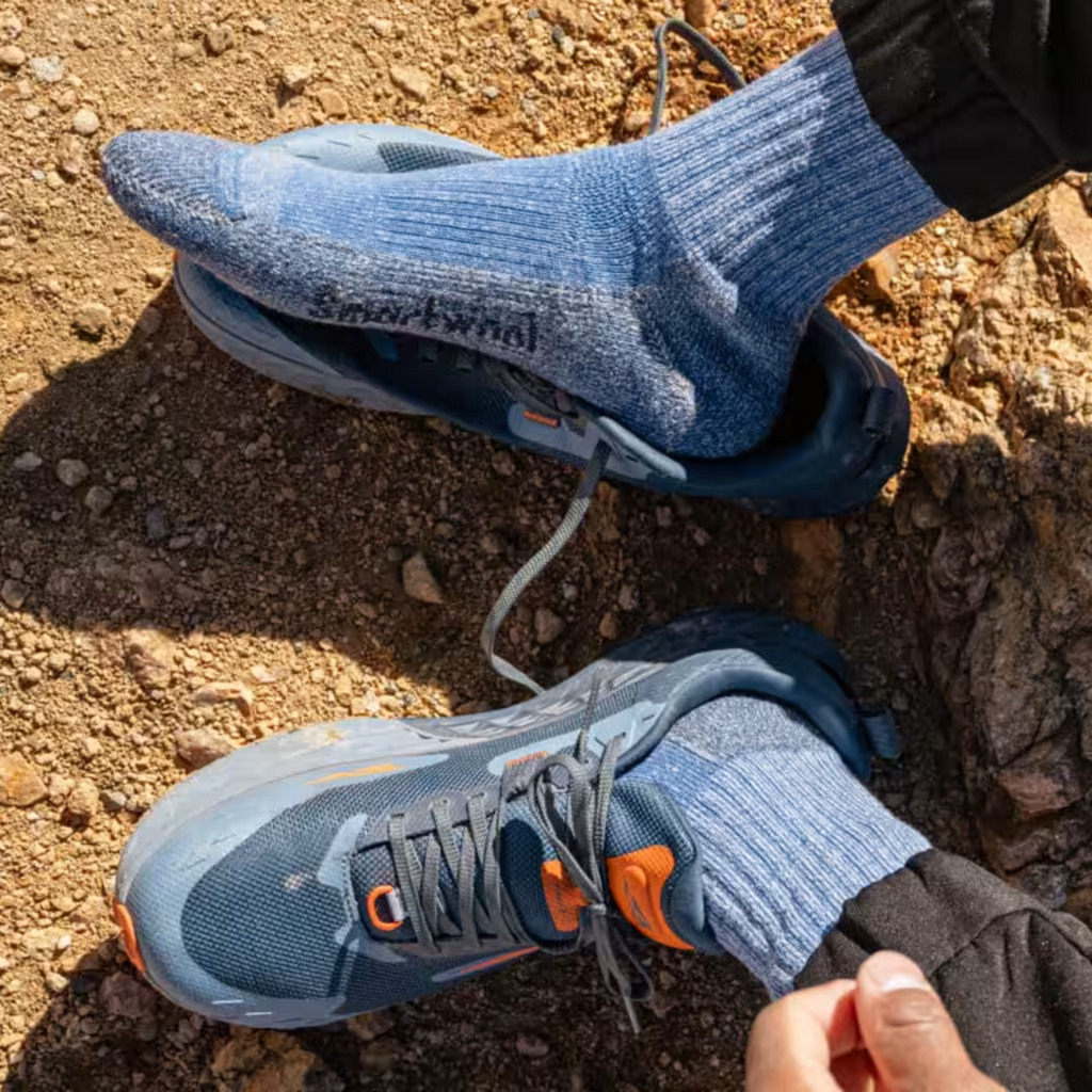 Blue athletic shoes with orange accents worn on a rocky surface