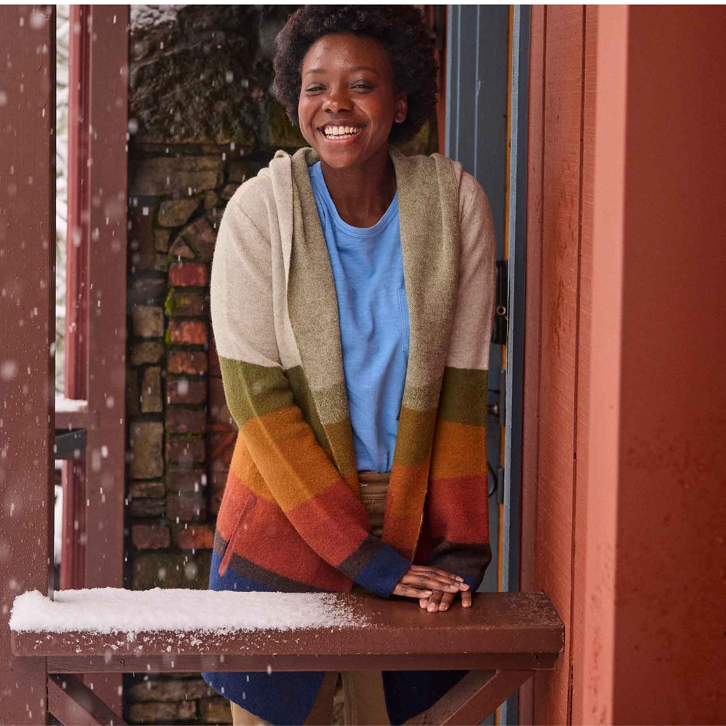Person wearing a colorful sweater standing in front of a door with snow falling