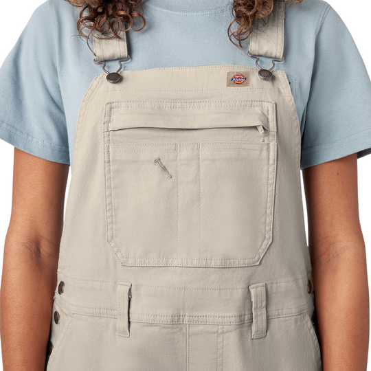 Dickies Women's Double Front Bib Overalls - Rinsed Stone on a female model on a white background. Close up of the chest pocket