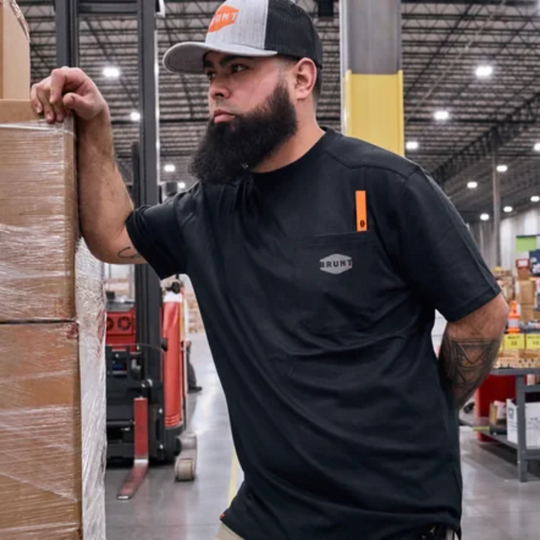Brunt Men's The Martin Pocket Tee - Black on a male  model. Showing a warehouse in the background.