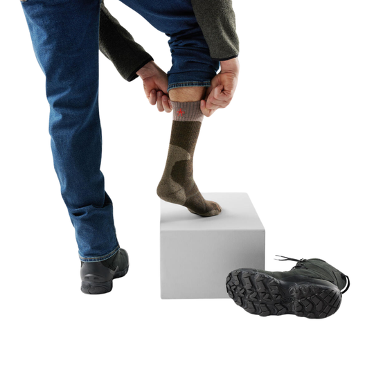 Person putting on olive socks with a white background