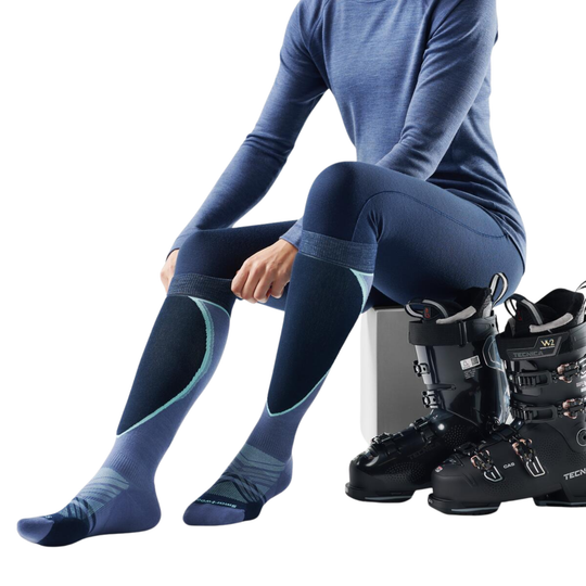 Person wearing blue ski pants and socks with black ski boots on a white background