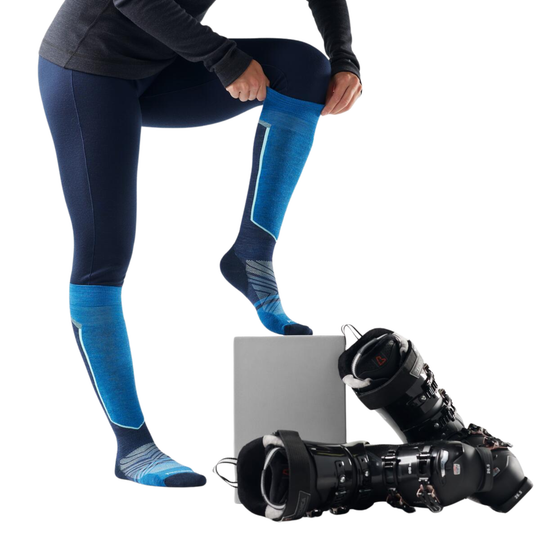 Person wearing blue ski socks and leggings with ski boots on a white background