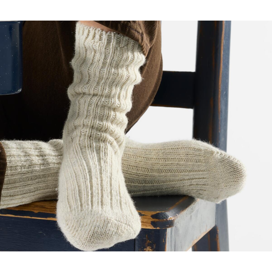 Close-up of beige knitted socks on a wooden chair.