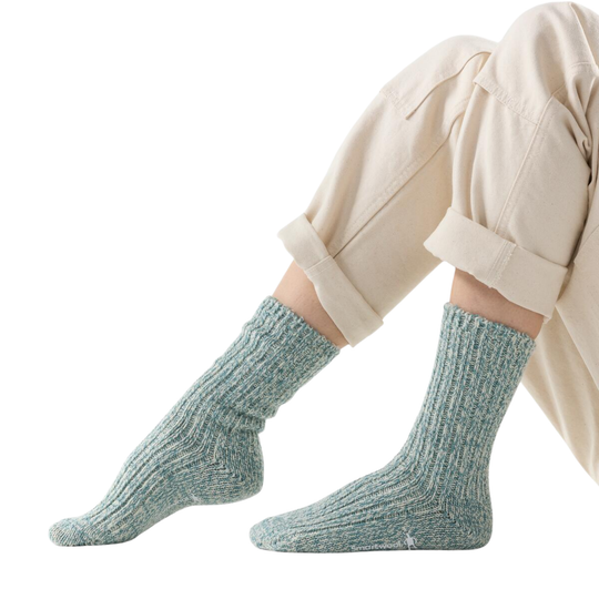 Light blue socks worn with beige pants on a white background