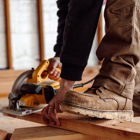 Person using a circular saw on a wooden surface with a blurred background