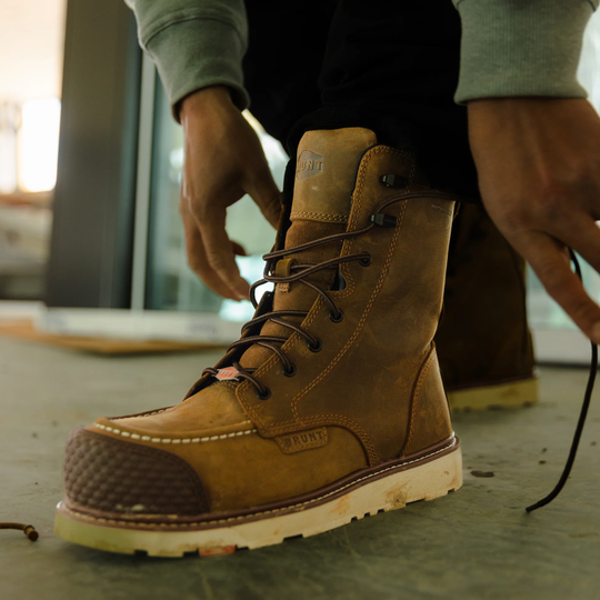 Brown work boot being worn with a blurred indoor background
