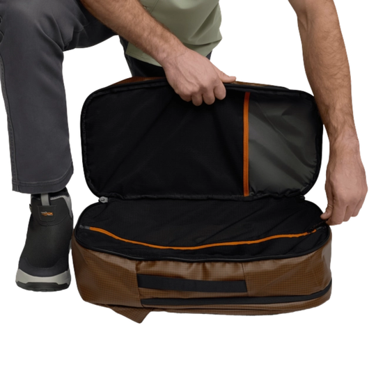 Person opening a black and brown travel bag with orange accents on a white background