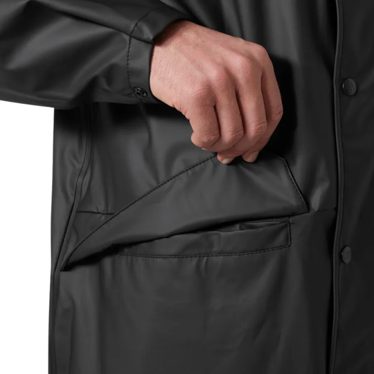 Close-up of a person wearing a black raincoat with a hand in the pocket.