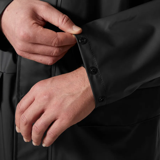Close-up of hands adjusting a black jacket with button details.