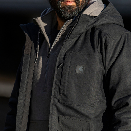 Person wearing a black Carhartt jacket with a blurred background