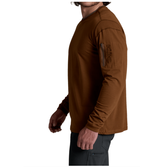 A man wearing a brown long-sleeve performance shirt with a vertical zippered pocket on the upper sleeve, shown in a side profile against a white background.