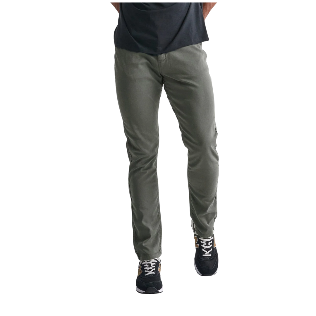 A person wearing slim-fit grey pants, a dark navy t-shirt, and black sneakers with white laces, shown from the waist down against a plain white background.
