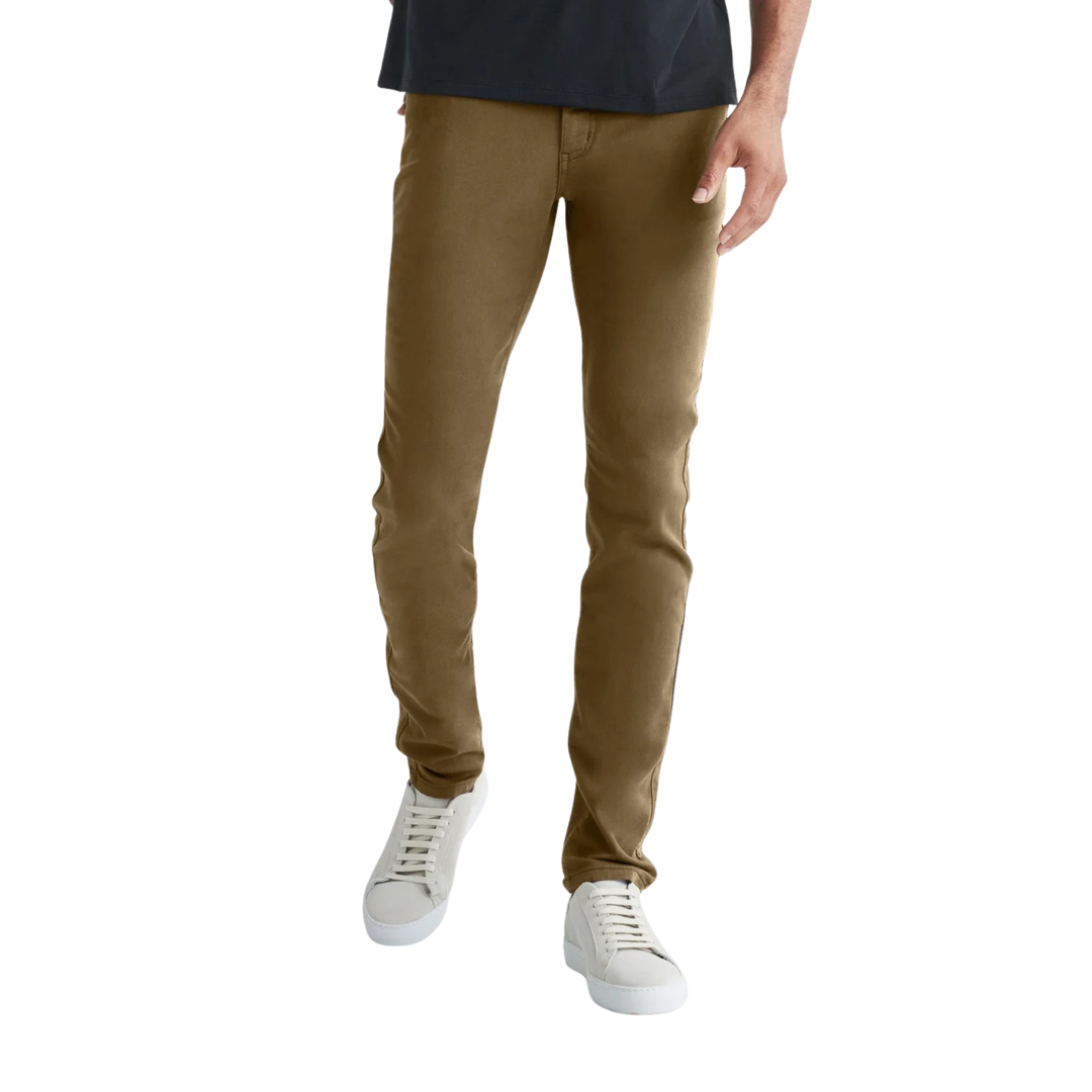 A person wearing slim-fit brown pants with a dark navy t-shirt and white sneakers, shown from the waist down on a plain white background.