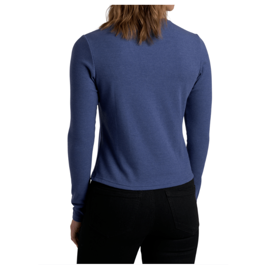 A woman shown from the back wearing a fitted long-sleeve knit top in a medium periwinkle blue color, paired with black pants, against a plain white background.