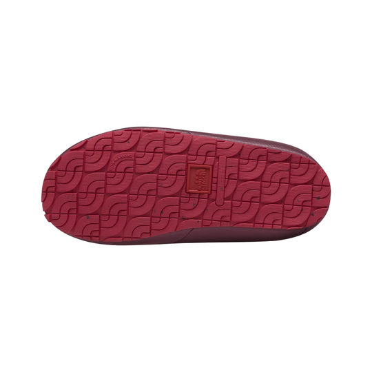 The red textured rubber outsole of a shoe, showing a repeating interlocking wave pattern and a small square brand patch in the center, isolated on a white background.
