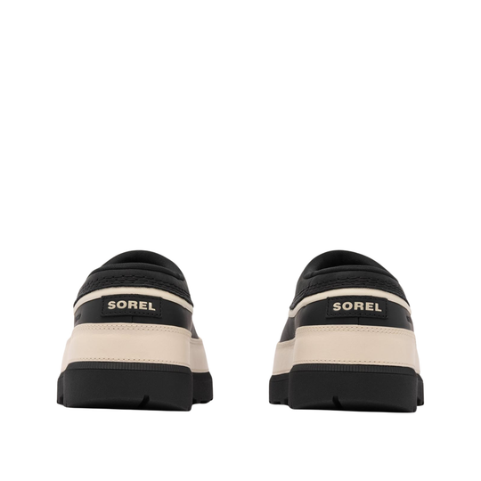 A pair of Sorel slip-on shoes shown from the back, featuring a black upper and sole with a beige midsole stripe and gold 'SOREL' branding.
