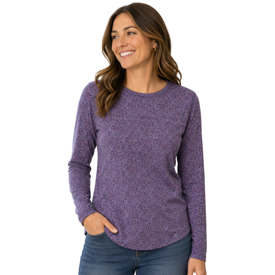 Female model wearing a long sleeve top with a repeating floral pattern in shades of purple, blue, and brown on a plain white background.
