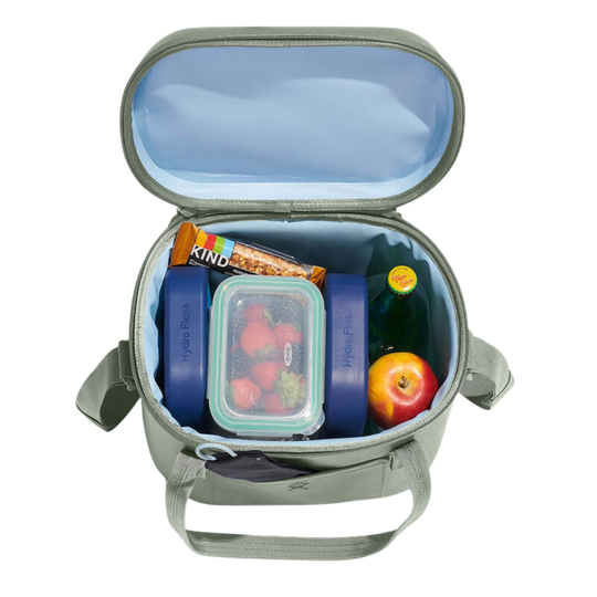 An open gray insulated lunch bag filled with food items, including a container of strawberries, a Kind bar, and a bottle, on a white background.