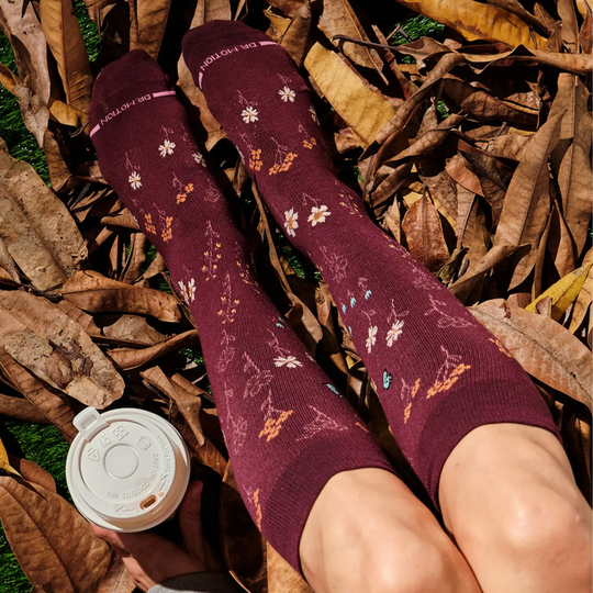 Dr. Motion Women's Alpine Garden Knee High Compression Socks - Dark Cherry with a coffee cup to the side and autumn leaves
