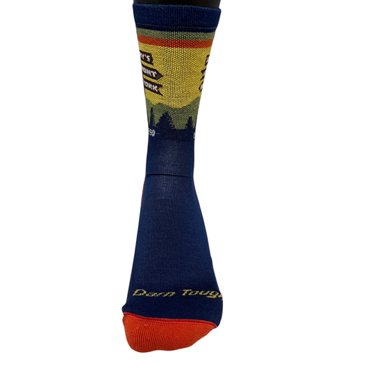 A single crew sock shown on a white background, featuring a navy blue lower leg and foot with a bright orange toe, yellow and green landscape graphic, and a red stripe near the cuff. The text 'Darn Tough' is visible near the ankle.