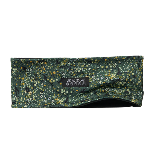 A dark green patterned headband with a dense floral and bird print, featuring a black SKIDA brand label on the front, set against a plain white background.