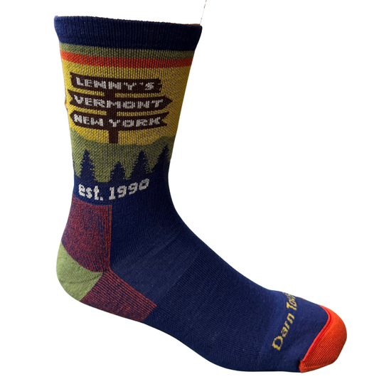 A single crew sock with a navy blue body, a yellow and green mountain landscape graphic on the upper section, and 'Darn Tough' written in yellow on the toe cap, set against a plain white background.
