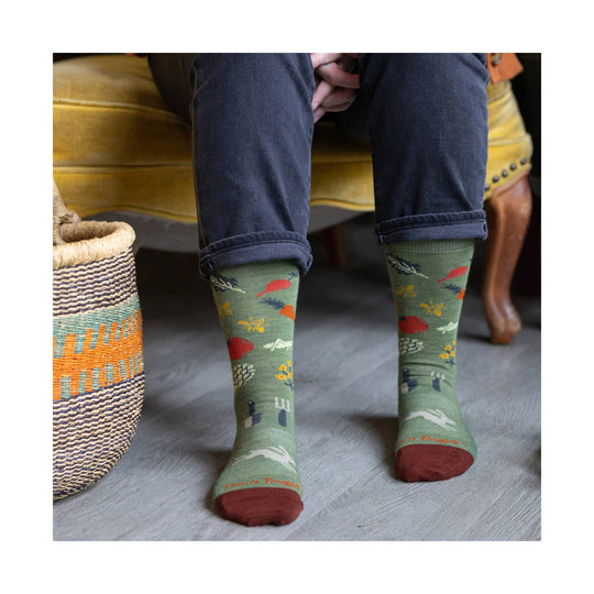 Green patterned crew socks with red toes and heels, worn with cuffed dark jeans.