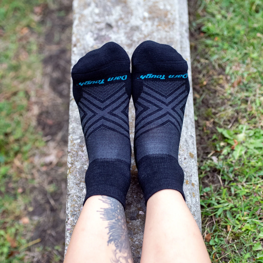 Pair of black ankle running socks with blue toe text and gray chevron pattern