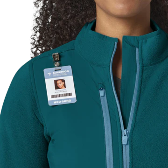 Person wearing a teal jacket with a name tag on a white background