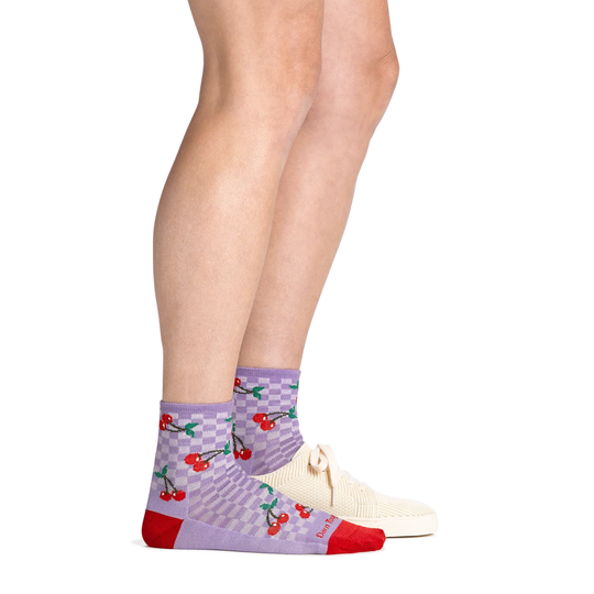 Purple socks with cherry design worn by a person on a white background