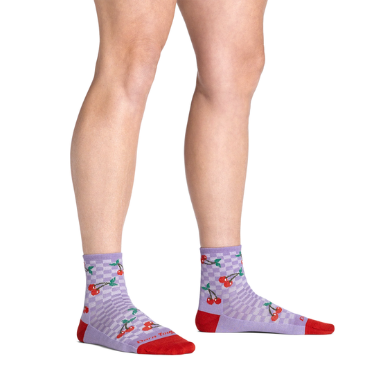 Purple socks with cherry pattern worn by a person on a white background