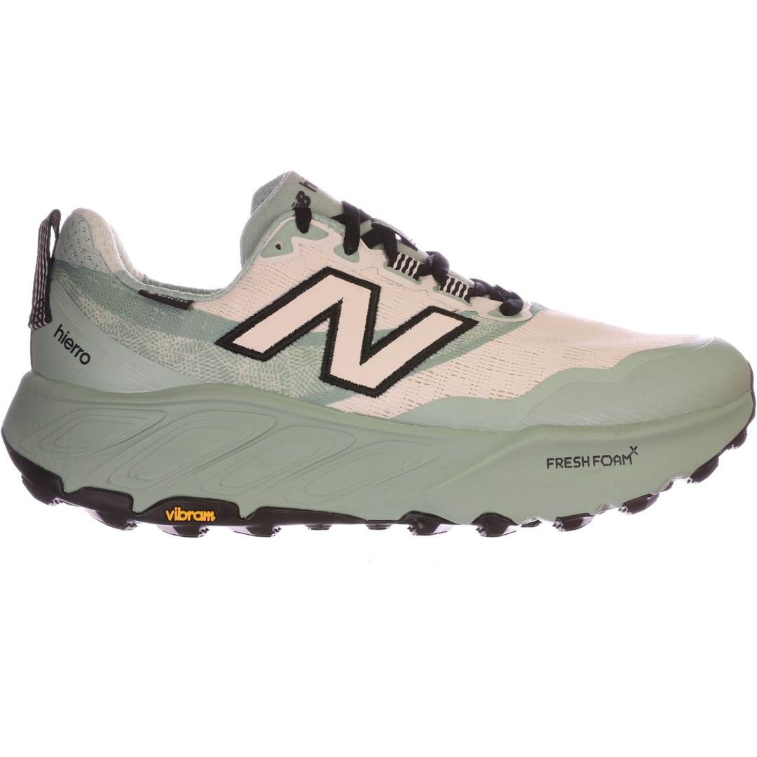 Light green and white trail running shoe with black laces, large side logo, and rugged Vibram sole