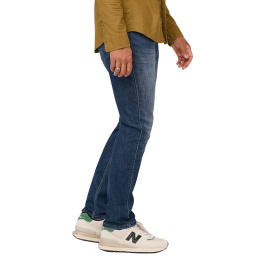Person wearing blue jeans and a mustard jacket on a white background