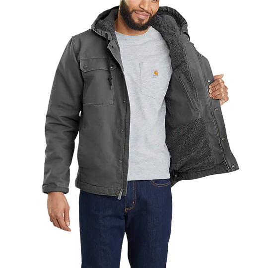 Man wearing a gray jacket with a hood, gray shirt, and blue jeans on a white background