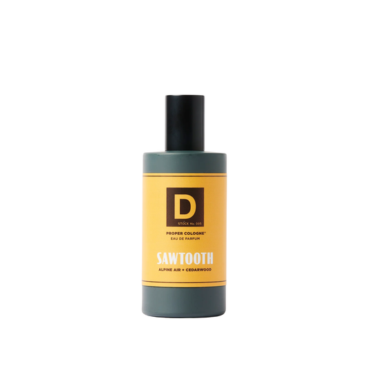 Dark gray cologne bottle with black cap and yellow label reading Sawtooth, on a white background