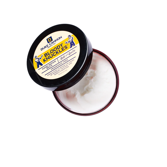 Open jar of hand repair balm with cream-colored product inside and a black lid