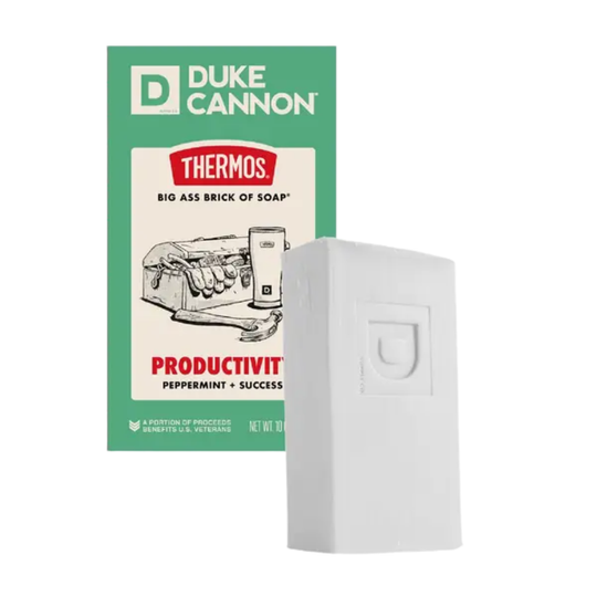 White soap bar in front of green Duke Cannon Thermos packaging, with visible text and a white embossed box.