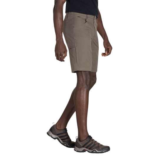 Person wearing beige cargo shorts and black Adidas shoes on a white background
