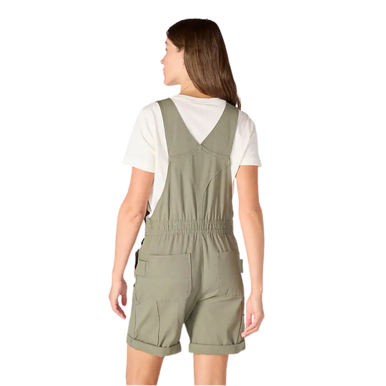Woman wearing a green overalls with a white shirt underneath on a white background