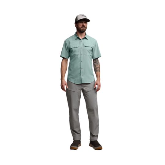 Man wearing a light green shirt and gray pants on a white background